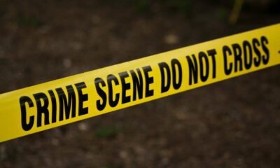 Close-up of crime scene tape with 'Do Not Cross' text, outdoors setting.
