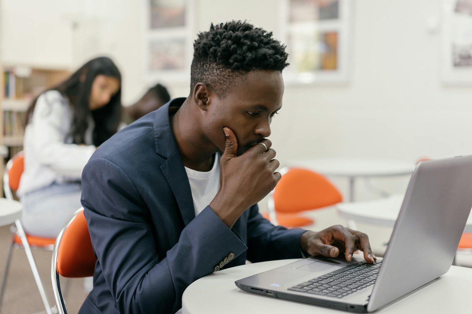 man in blue suit jacket using macbook pro